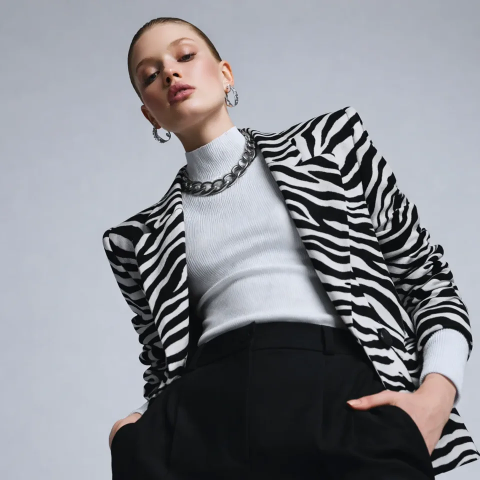 Person in a zebra-print blazer, white top, and black trousers, with a chunky silver chain and earrings — illustrating a Bold style identity